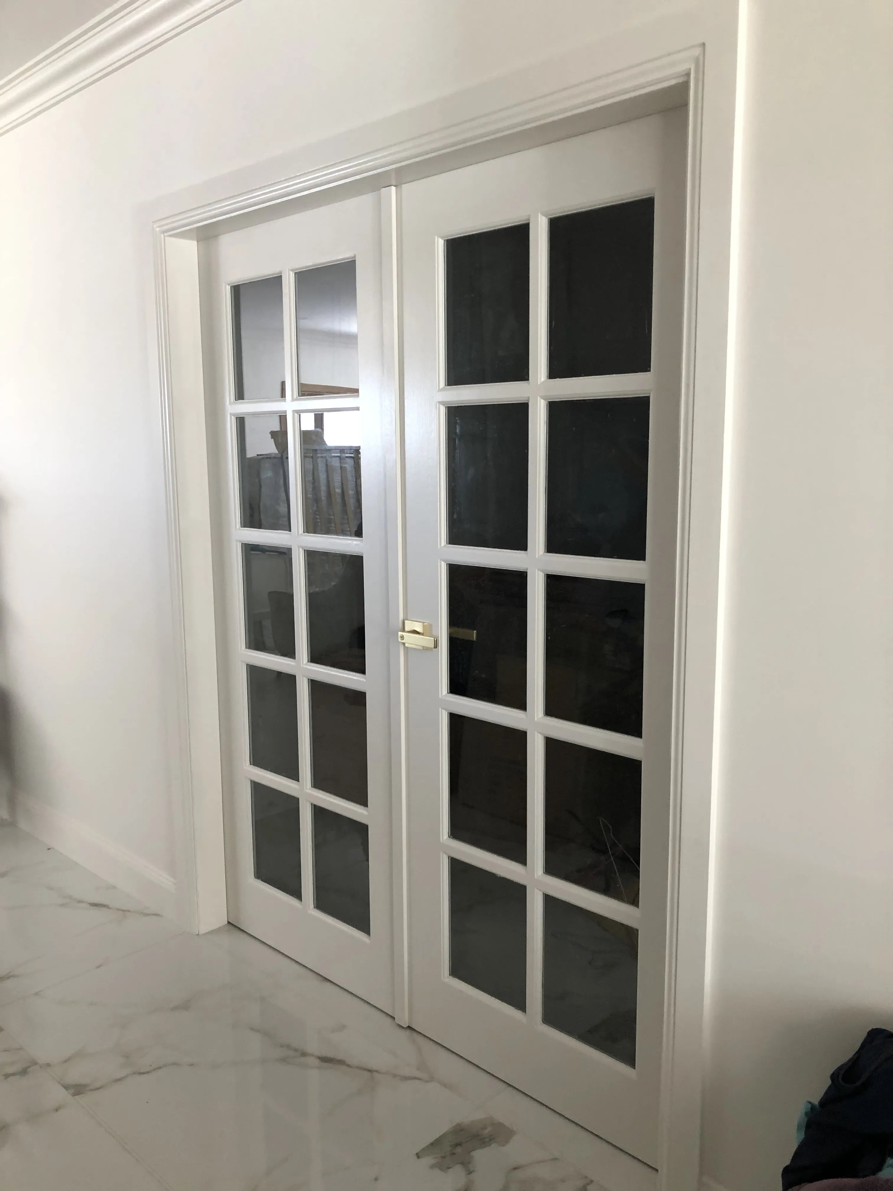 French doors installed in double door configuration. French doors with clear glass and painted white with brass lever. 90mm colonial architraves installed around door frame.