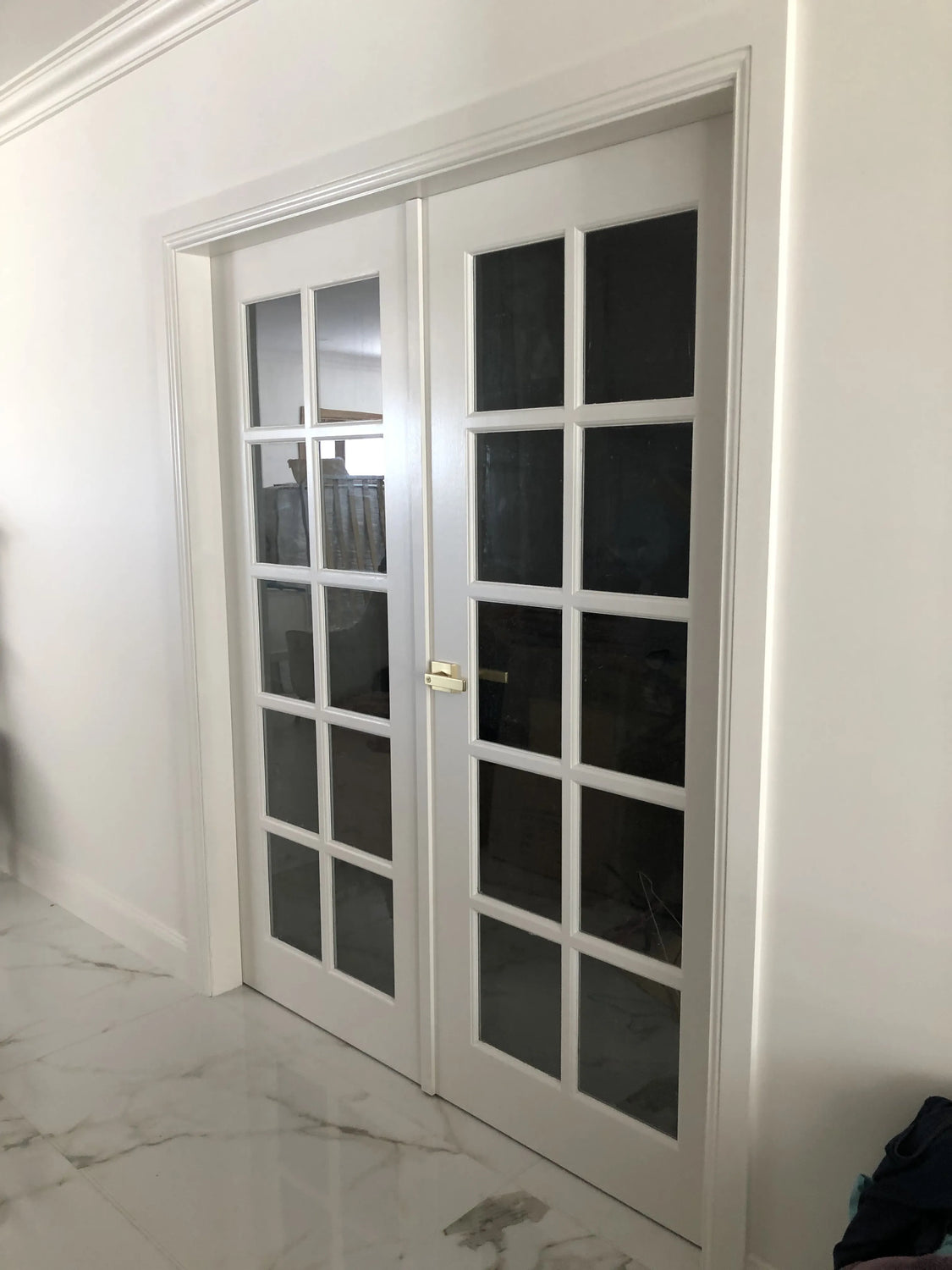 French doors installed in double door configuration. French doors with clear glass and painted white with brass lever. 90mm colonial architraves installed around door frame.