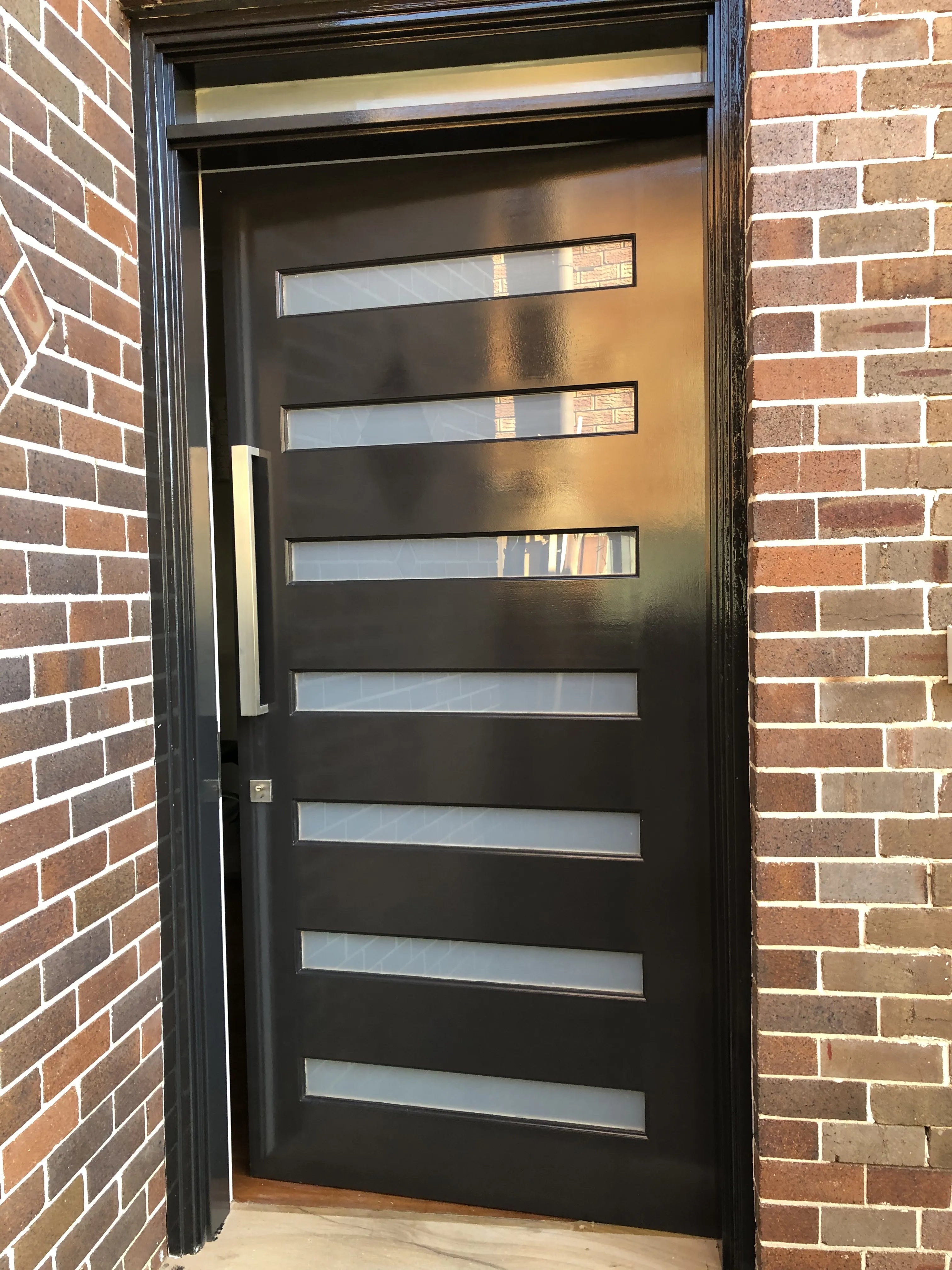Front door with 7 frosted glass panels, painted black with matching door frame installed in Sydney.