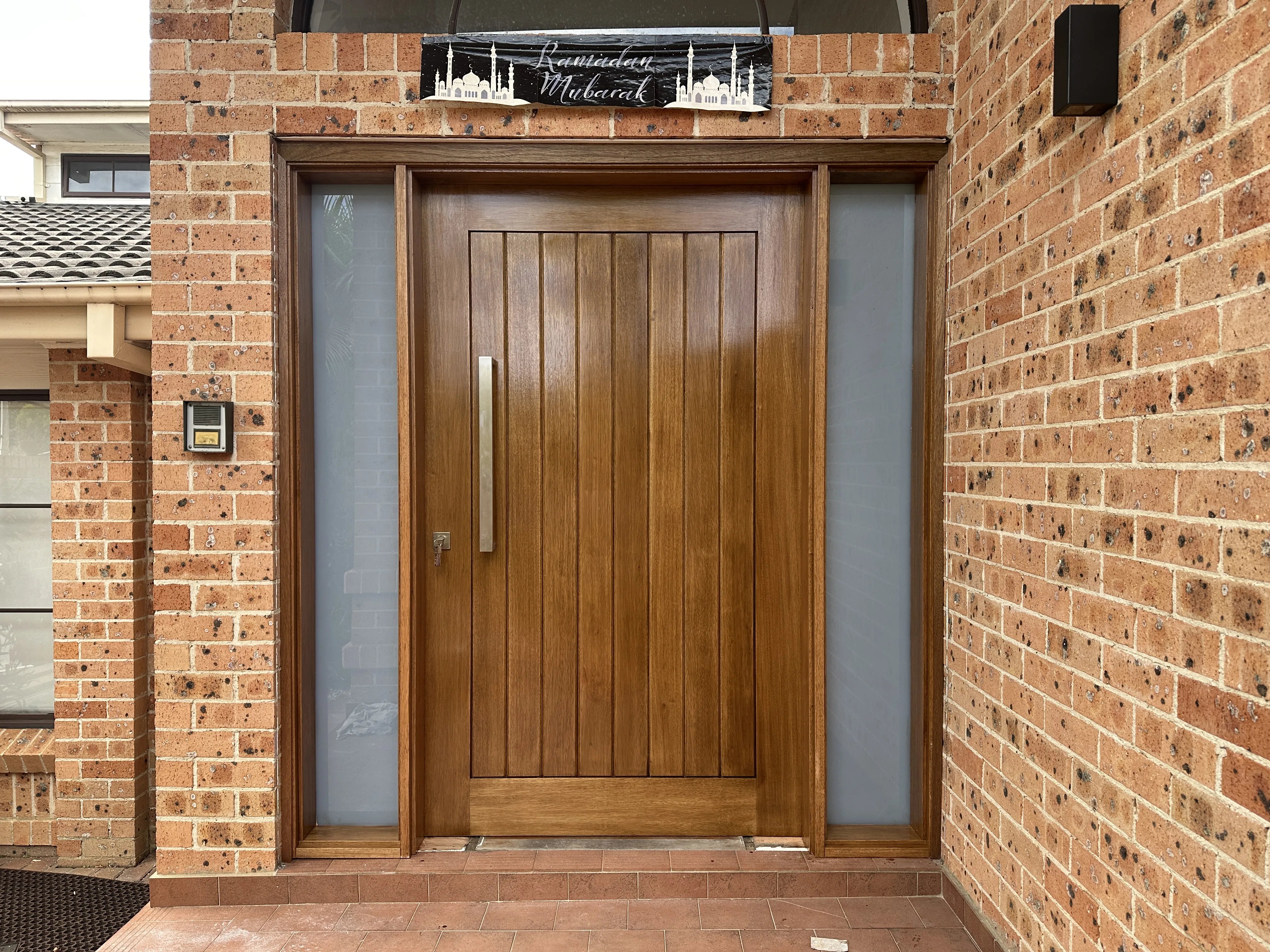 2040x1200mm joinery construction front door stained and installed with chrome handle. Fixed frosted glass side panels on each side of door.