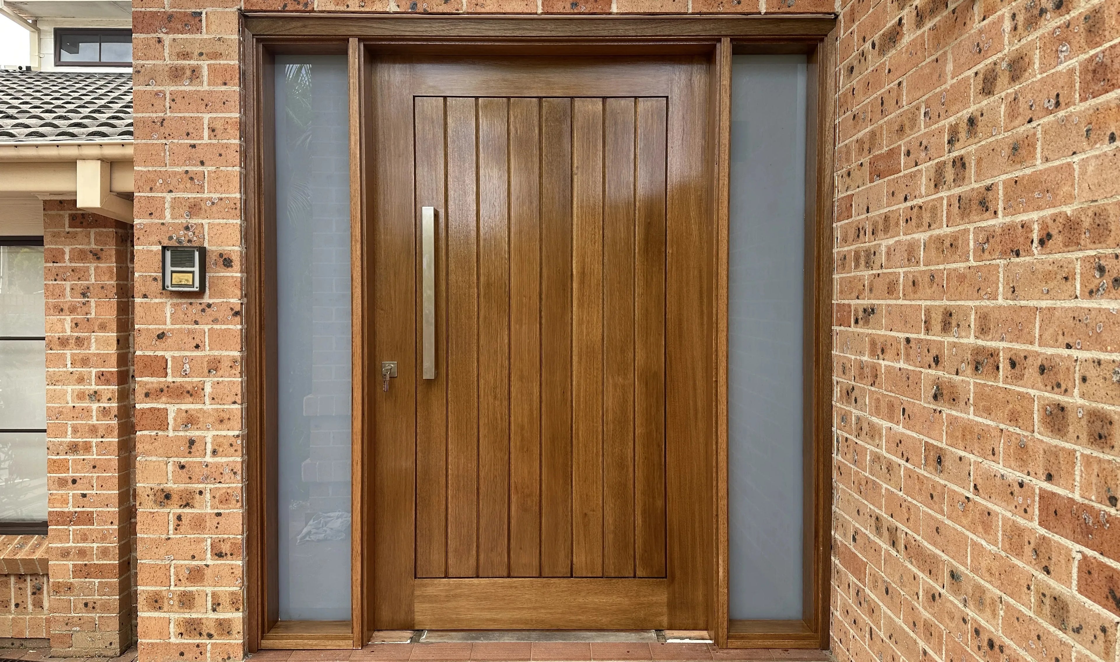 Stained solid wood front door installed with glass side panels in Sydney