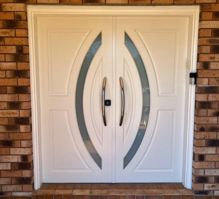 White double doors with decorative glass panels on a brick wall.