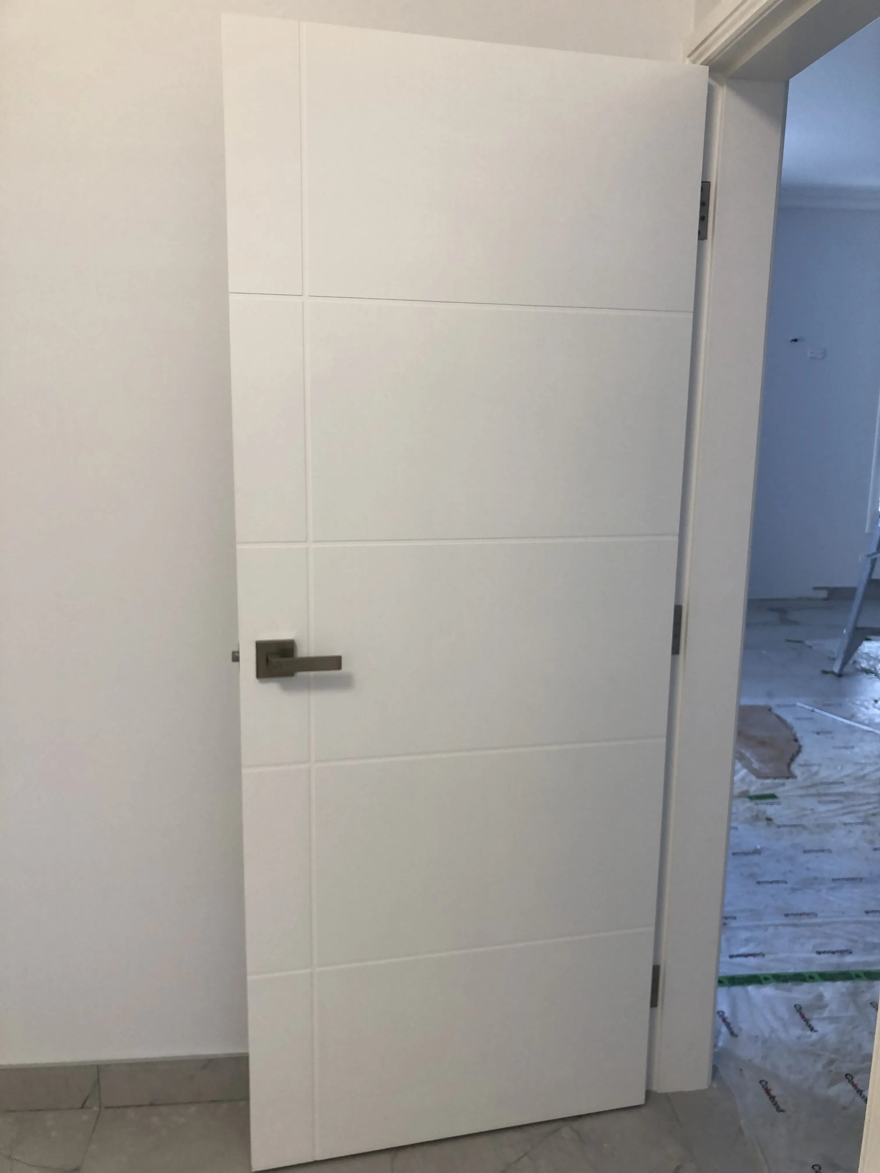 Modern internal door with narrow carved lines, painted white and square profile handle installed.